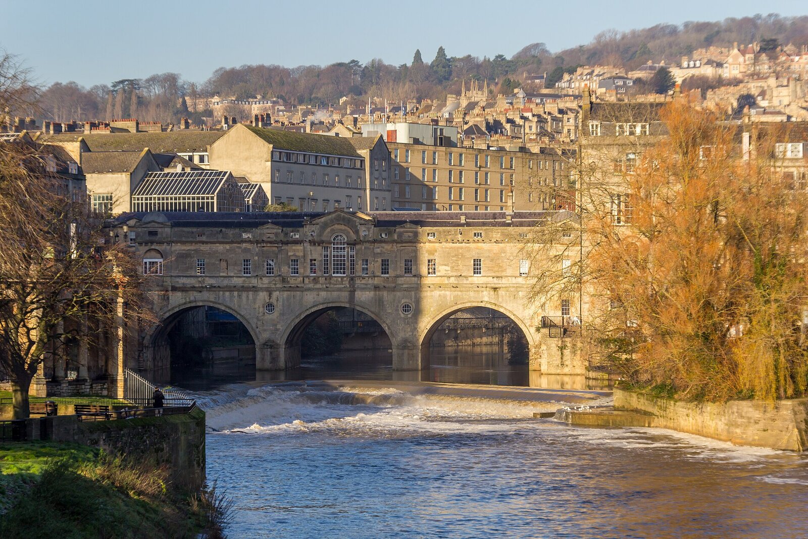 Pulteney Bridge in Bath - the elegant Georgian bridge and weir over the River Avon in golden light, with the city behind