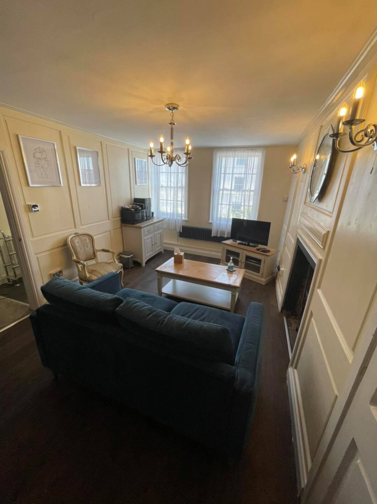 Elegant, cream-panelled pub dining room with deep navy-blue velvet sofa, chandelier and fireplace