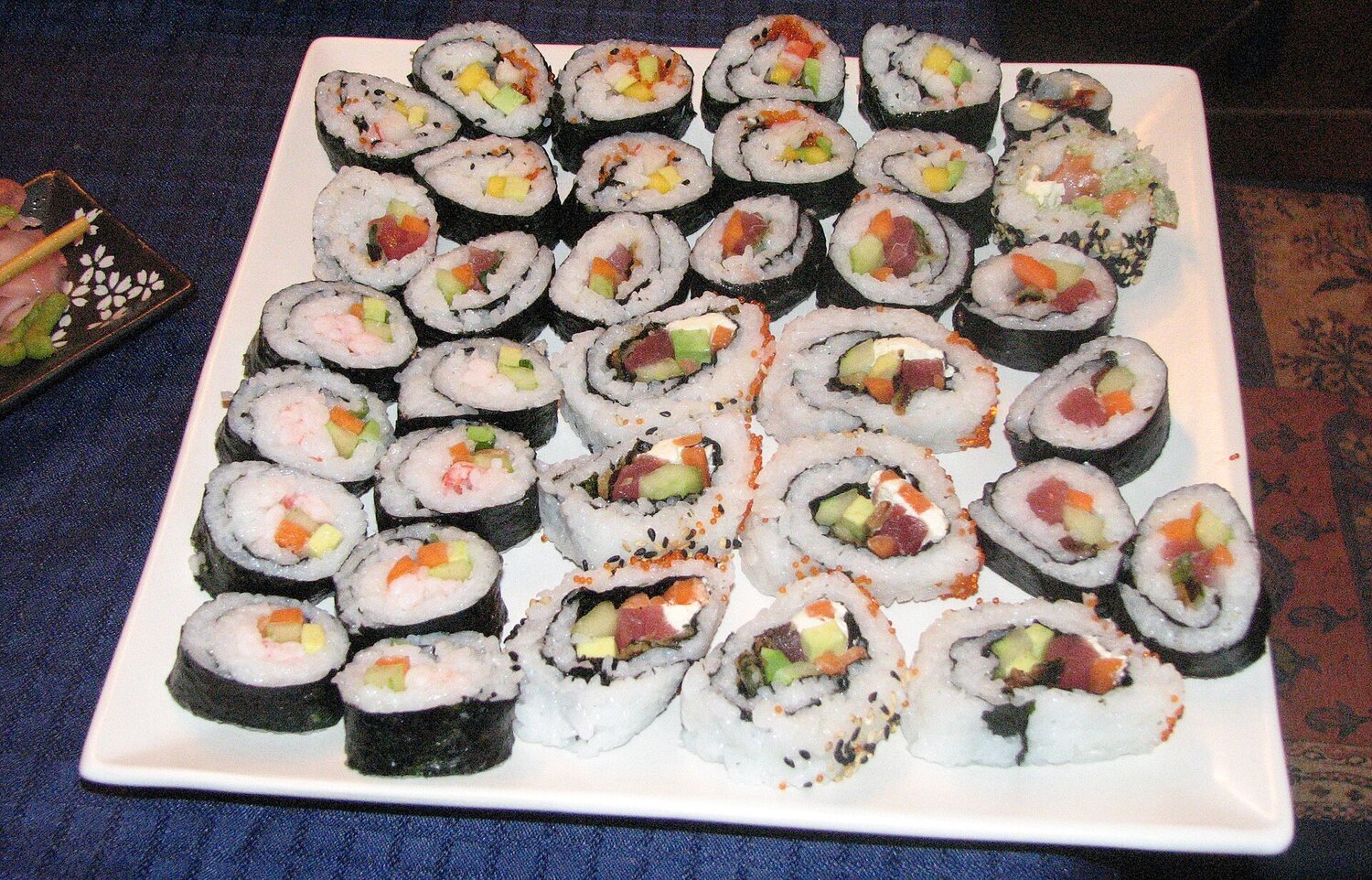 Assorted hand-made sushi rolls and maki on a white platter