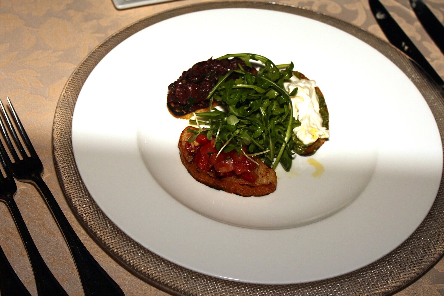 Elegant plated Italian starter with bruschetta, olive tapenade and mozzarella on fine white plate